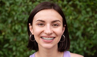 A young girl smiling with metal braces on her teeth