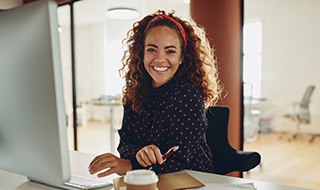 Woman smiling while working on computer in office