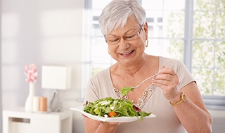 A happy older lady eating a fresh salad