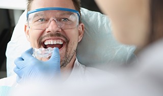 A dentist placing a mouthguard over a man’s teeth