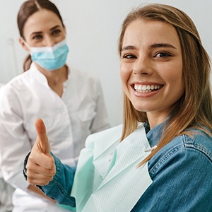 Patient smiling while giving thumbs up in treatment chair