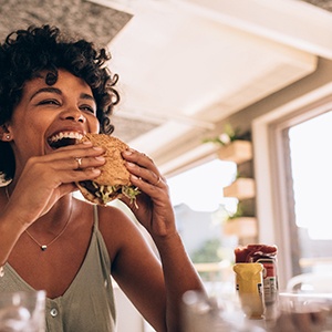 Woman smiling while eating burger at restaurant